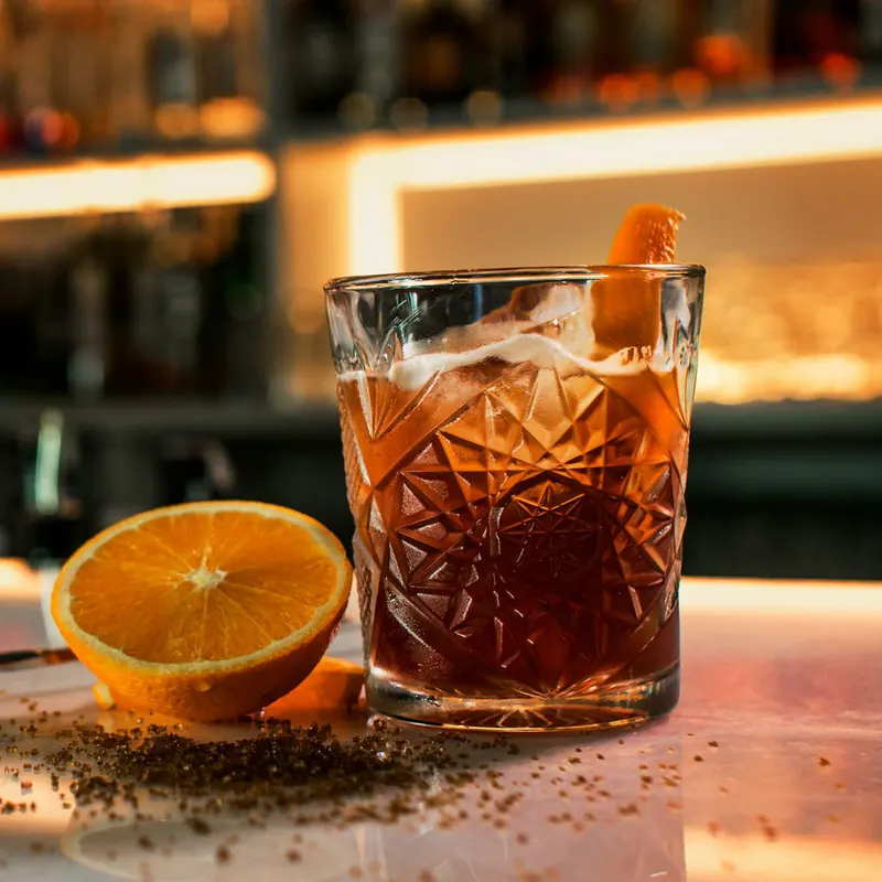 Stock photo: a cocktail on a bar top with a warm, blurred back bar